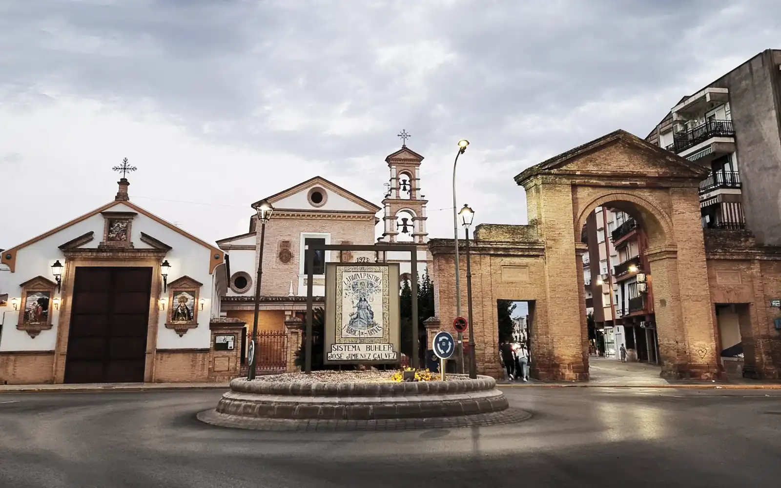 Conjunto monumental de una plaza municipal con iglesia y arco de piedra, representativo de una ruta cultural local